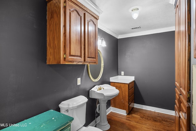 bathroom with crown molding, toilet, baseboards, wood finished floors, and visible vents