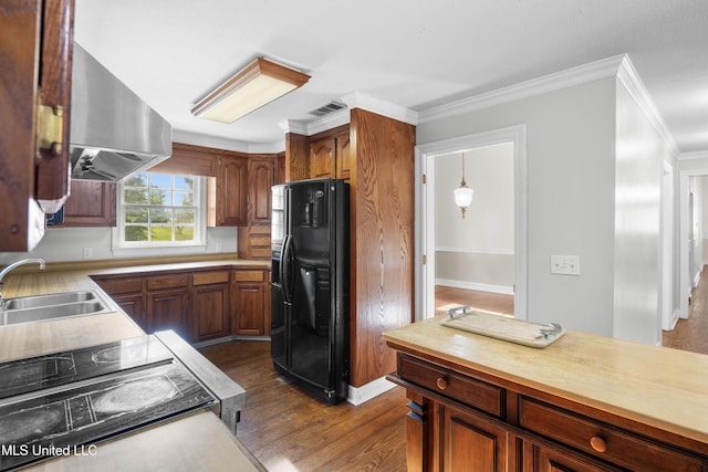 kitchen featuring wall chimney range hood, a sink, dark wood-type flooring, visible vents, and black fridge with ice dispenser