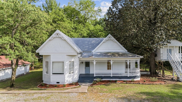 victorian-style house featuring covered porch, a front yard, and crawl space