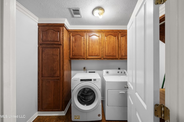 clothes washing area with visible vents, wood finished floors, a textured ceiling, washing machine and clothes dryer, and cabinet space