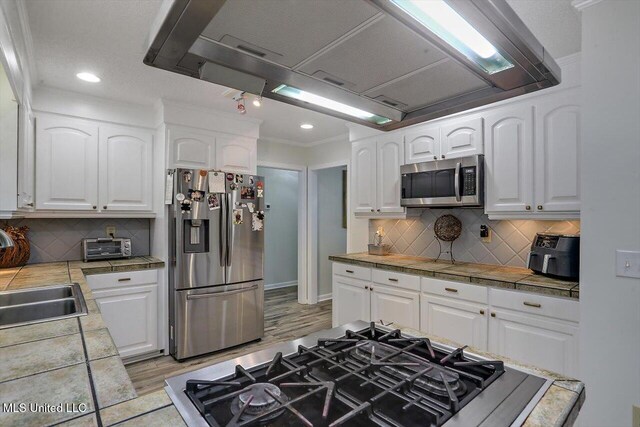 kitchen with white cabinetry, stainless steel appliances, and tile counters