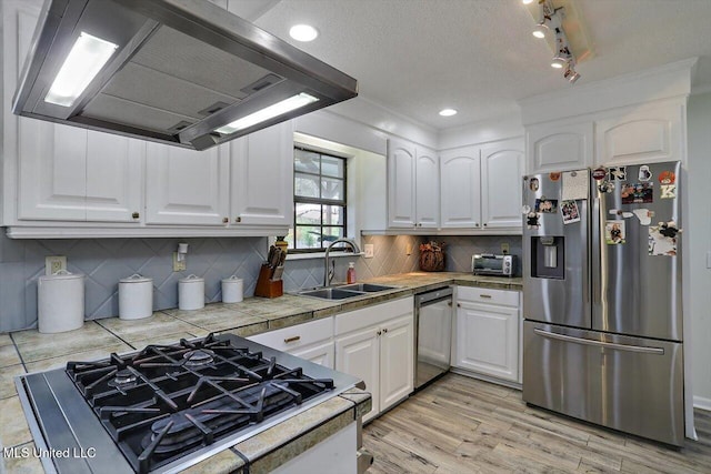 kitchen featuring sink, a textured ceiling, stainless steel appliances, white cabinets, and range hood