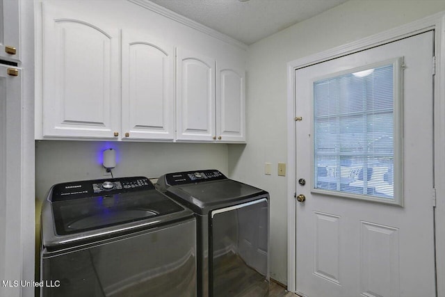 laundry room with a textured ceiling, washing machine and clothes dryer, wood-type flooring, and cabinets