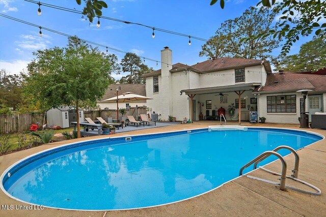 view of pool featuring a shed and a patio