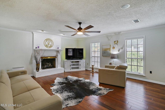 living room with ceiling fan, a fireplace, ornamental molding, and dark hardwood / wood-style floors