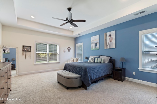 carpeted bedroom with a tray ceiling and ceiling fan