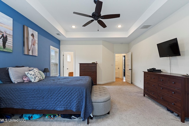 carpeted bedroom featuring ceiling fan and a tray ceiling