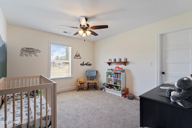 carpeted bedroom featuring a nursery area and ceiling fan