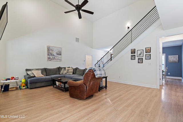 living room featuring a high ceiling, light wood-type flooring, and ceiling fan