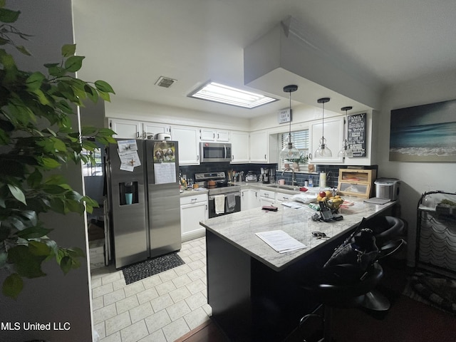 6530 Koula Dr, Diamondhead, MS 39525 - kitchen with stainless steel appliances, a peninsula, white cabinets, tasteful backsplash, and light tile patterned flooring