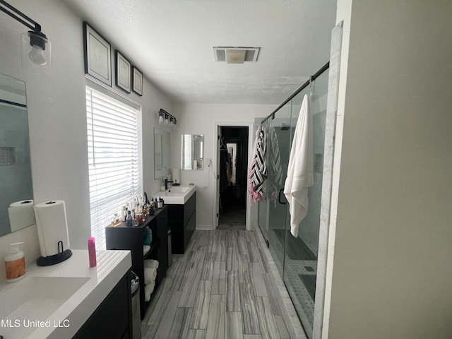6530 Koula Dr, Diamondhead, MS 39525 - bathroom with a shower stall, two vanities, wood finished floors, and a walk in closet
