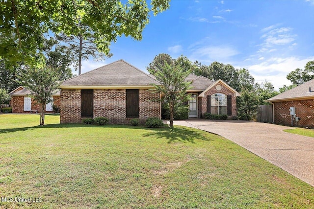 single story home featuring concrete driveway, brick siding, fence, and a front lawn