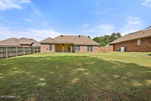 back of property featuring a fenced backyard, a lawn, and brick siding