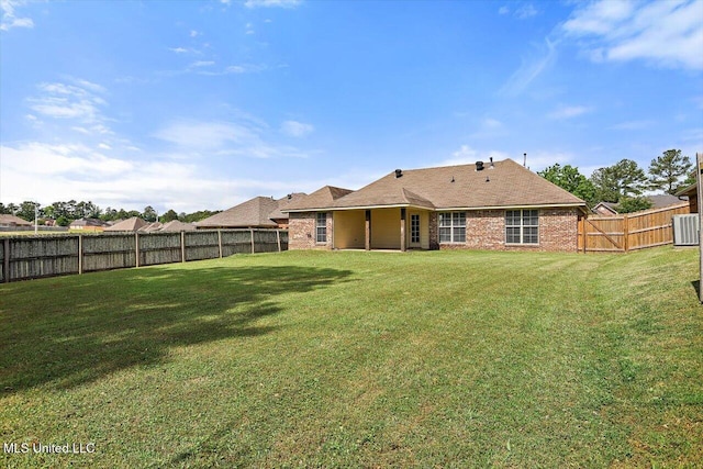 rear view of property with a lawn, a fenced backyard, and brick siding