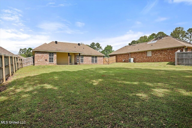 rear view of house featuring a fenced backyard, a yard, and brick siding