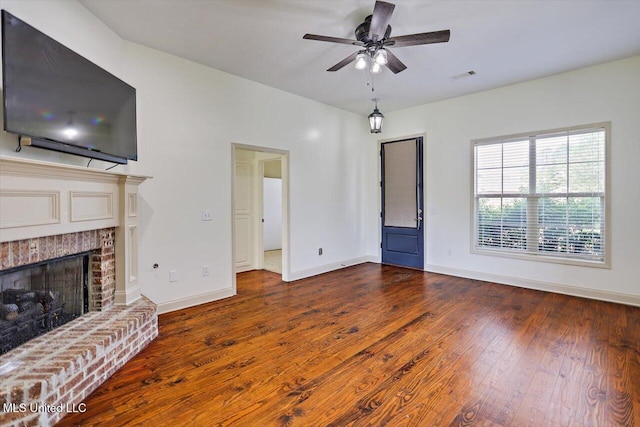 unfurnished living room with ceiling fan, visible vents, a fireplace, hardwood / wood-style flooring, and baseboards
