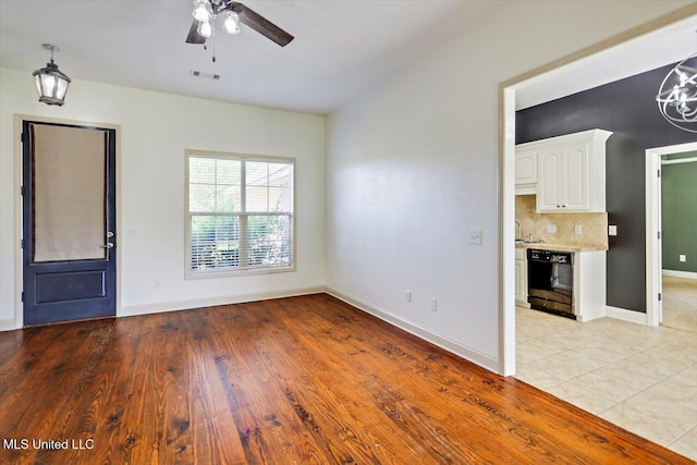 unfurnished living room featuring visible vents, light wood-style flooring, baseboards, and ceiling fan