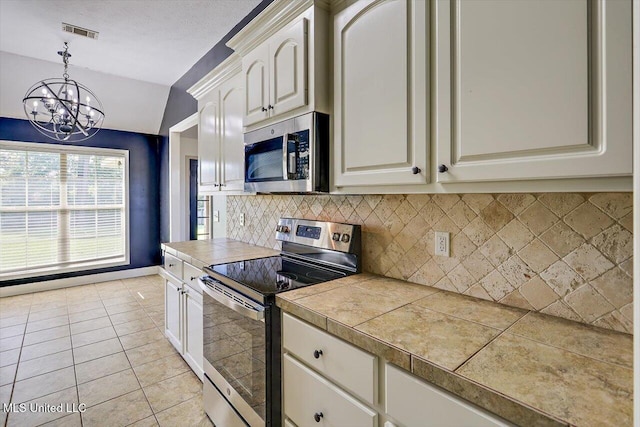 kitchen featuring appliances with stainless steel finishes, an inviting chandelier, decorative backsplash, visible vents, and pendant lighting