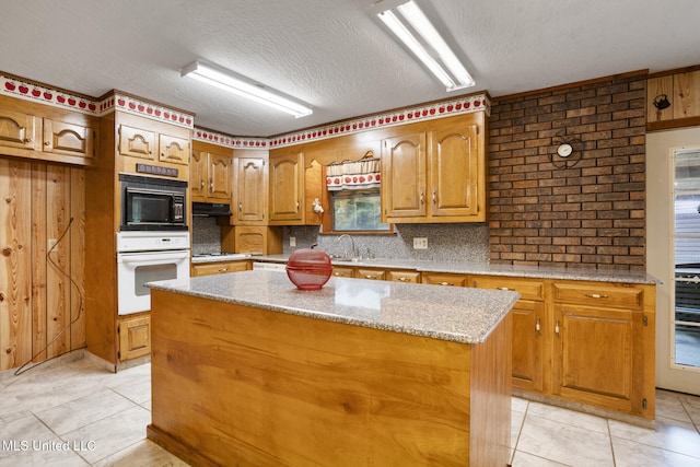 48 Brady Rd, Petal, MS 39465 - kitchen with white oven, black microwave, light tile patterned floors, a center island, and brown cabinets