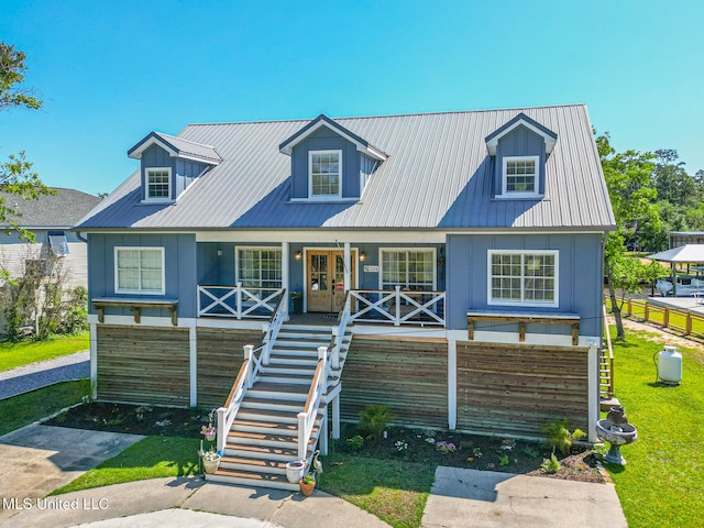 new england style home with a porch, stairway, metal roof, and a front lawn