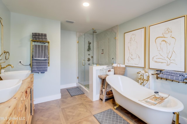 full bathroom with a shower stall, a freestanding bath, double vanity, and baseboards