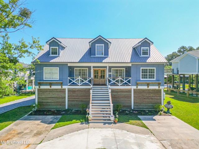 view of front facade with stairway, a porch, french doors, metal roof, and a front yard