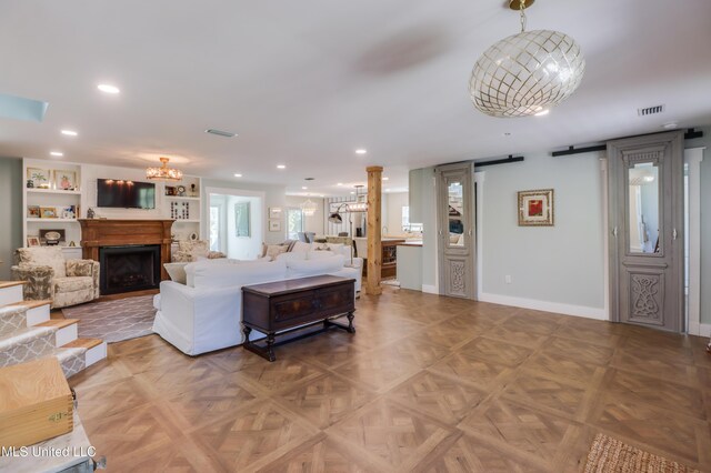 living room featuring a chandelier, recessed lighting, baseboards, a fireplace, and decorative columns