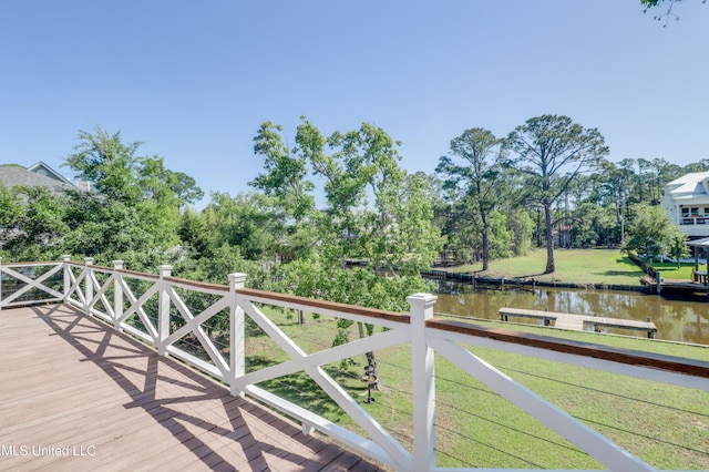 wooden deck with a water view, view of scattered trees, and a yard