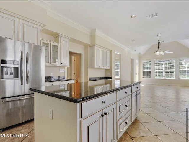 kitchen featuring crown molding, a center island, light tile patterned floors, dark stone countertops, and stainless steel fridge