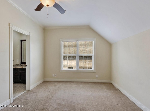 interior space with ceiling fan, lofted ceiling, light colored carpet, and ensuite bath