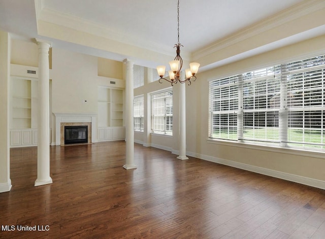 unfurnished living room with built in shelves, dark hardwood / wood-style flooring, crown molding, and ornate columns