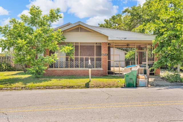 view of front facade with a front yard, a sunroom, and brick siding
