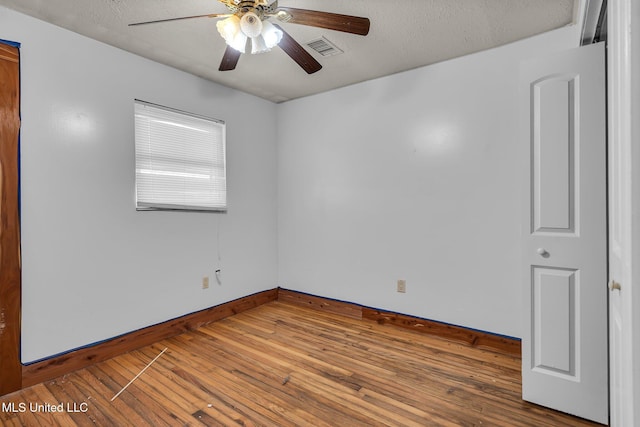 spare room featuring baseboards, ceiling fan, wood finished floors, and a textured ceiling