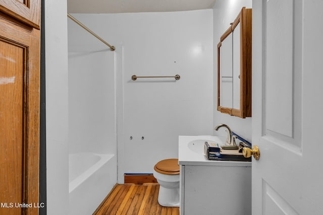 bathroom featuring vanity, toilet, wood finished floors, and  shower combination