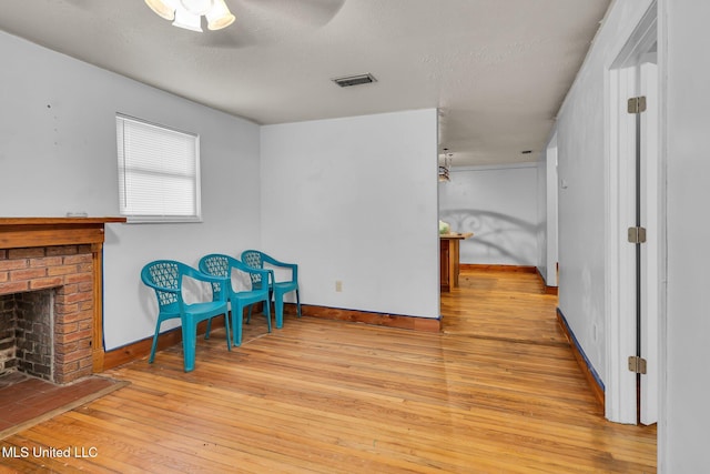 unfurnished room with hardwood / wood-style flooring, ceiling fan, a fireplace, baseboards, and a textured ceiling