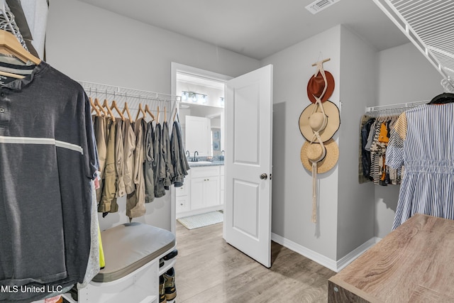 spacious closet with light wood finished floors and a sink