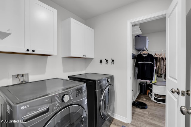 laundry room with cabinet space, washing machine and dryer, light wood-style flooring, and baseboards