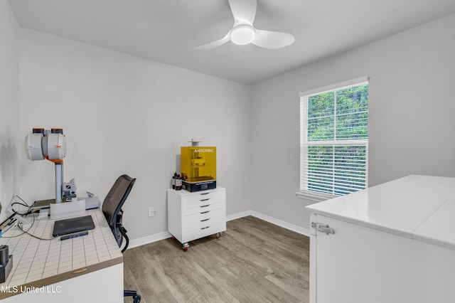 office space with light wood-type flooring, ceiling fan, and baseboards