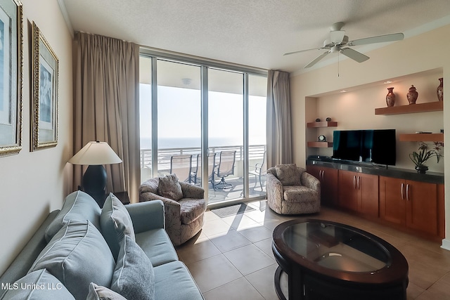 tiled living room featuring a textured ceiling, ceiling fan, floor to ceiling windows, and a wealth of natural light