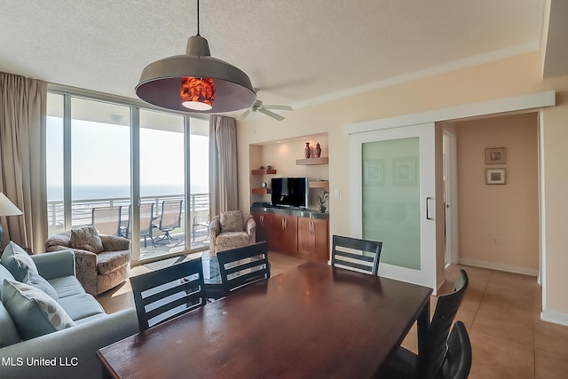 living room featuring tile patterned floors, a water view, ceiling fan, a textured ceiling, and floor to ceiling windows