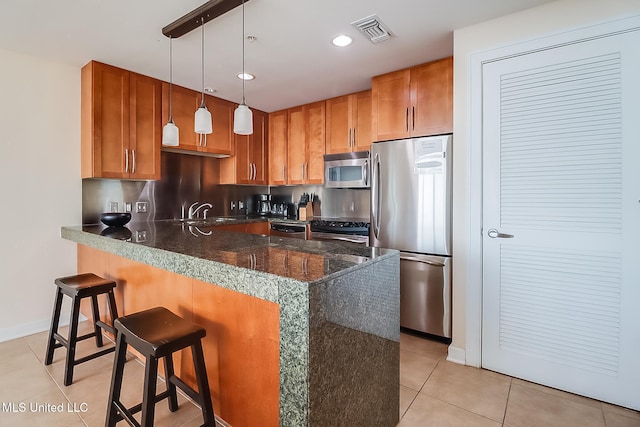 kitchen featuring sink, a breakfast bar, hanging light fixtures, stainless steel appliances, and light tile patterned floors