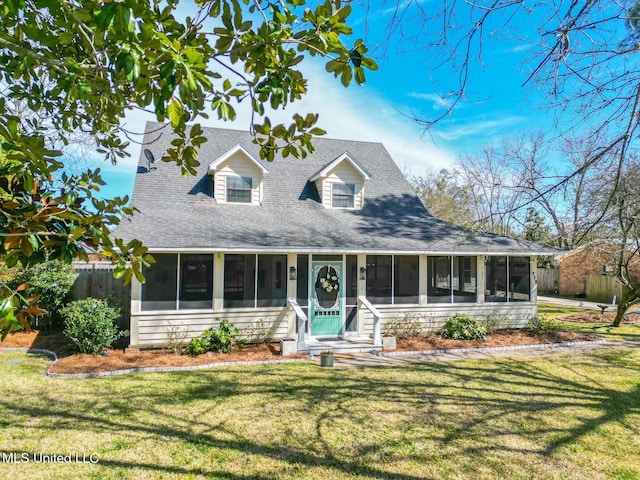 view of front of house featuring fence, a shingled roof, a front yard, and a sunroom