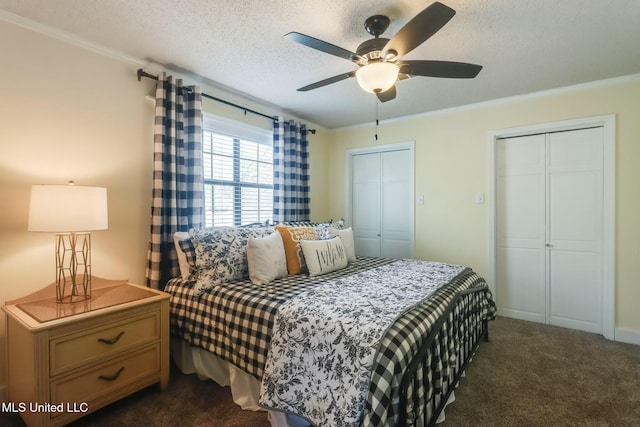 bedroom featuring a ceiling fan, multiple closets, a textured ceiling, and dark carpet