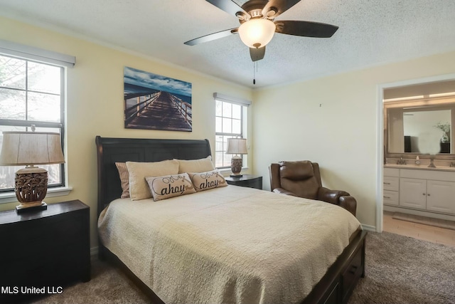 bedroom featuring baseboards, carpet flooring, ensuite bathroom, a textured ceiling, and a ceiling fan