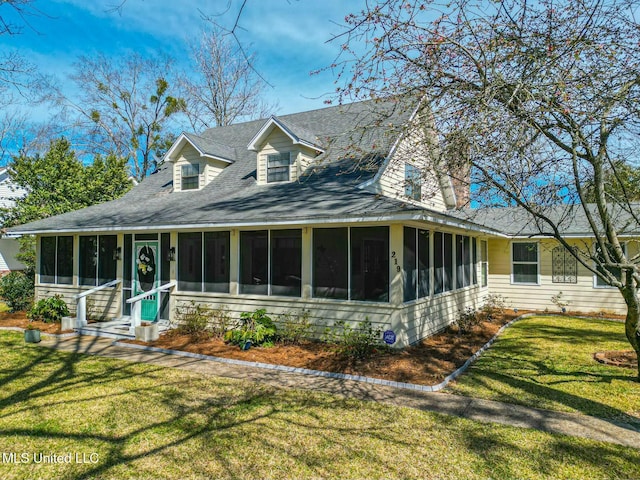 view of front of house with roof with shingles, a front lawn, and a sunroom