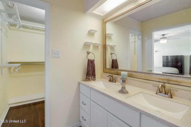 bathroom featuring a sink, baseboards, wood finished floors, and double vanity