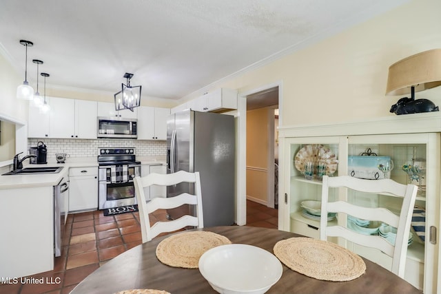 dining area with dark tile patterned floors, an inviting chandelier, and ornamental molding