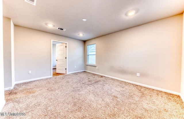 carpeted spare room featuring baseboards and visible vents