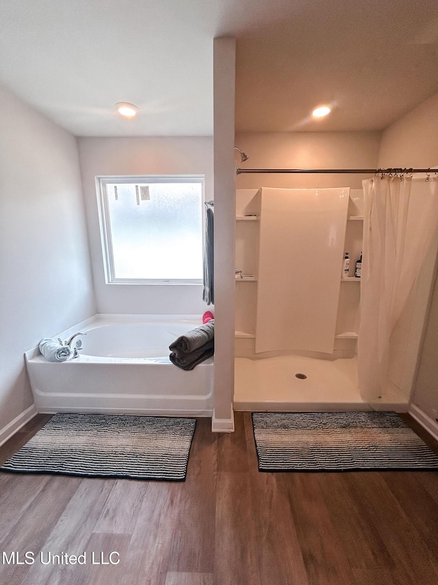 bathroom featuring curtained shower, baseboards, a garden tub, and wood finished floors