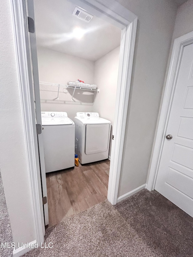 washroom featuring wood finished floors, visible vents, laundry area, carpet flooring, and washer and clothes dryer